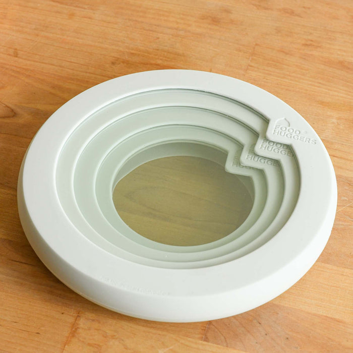 Soft white food hugger lids in soft white nested inside of each other.