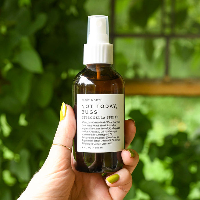 Hand holding amber bottle of bug spray from Slow North. Citronella Spritz. Natural effective bug spray.