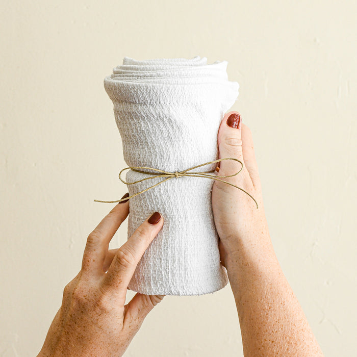 Hands holding cotton terrycloth rag bundle. Six rags wrapped inside of each other.