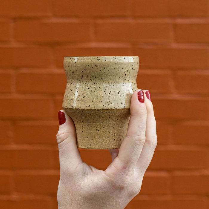 Hand holding ceramic sculptural tea cup. No handle. Natural glaze. Stackable. Made in Charleston SC.