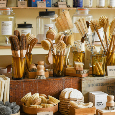 Wooden dish brushes in front of refillable home cleaning and body care products.