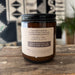 The back of an 8 ounce candle in a reusable amber glass jar. It is scented with organic essential oils of lavender, cedar, bergamot, and vetiver.