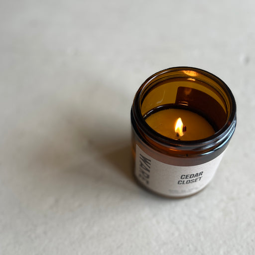 A sustainable candle in a reusable brown glass jar. It is scented with organic essential oils of lavender, cedar, bergamot, and vetiver.