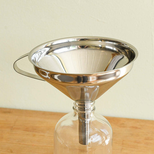 Stainless steel funnel set in narrow mouthed jar.