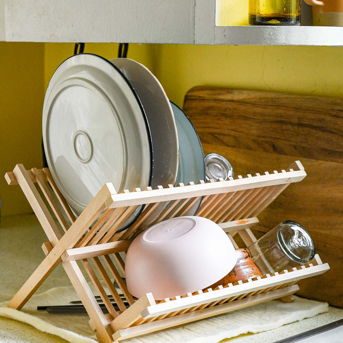 Beechwood foldable X drying rack. Pictured in kitchen with dishes. 