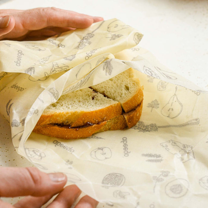 Large beeswax wrap being used to wrap a sandwich. 