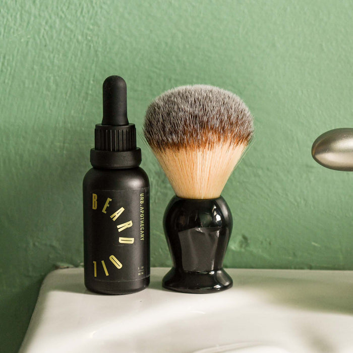 Beard oil in bathroom sitting next to shaving brush. From Urb Apothecary.