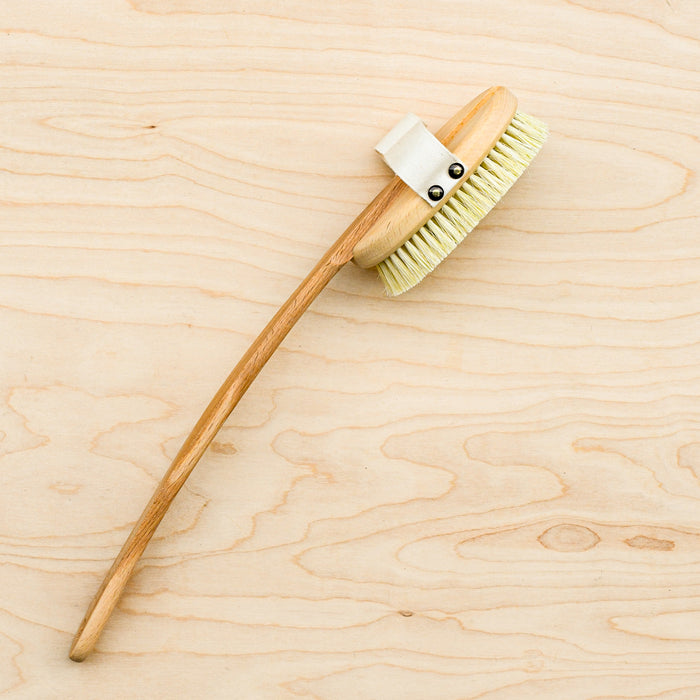 Bath brush with an attached handle and cotton hand strap.