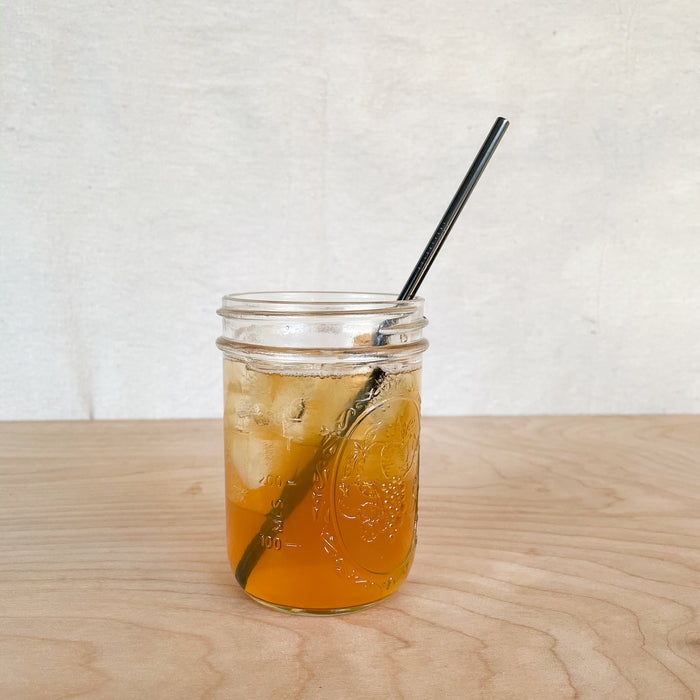 Reusable straight black metal straw in a drink.