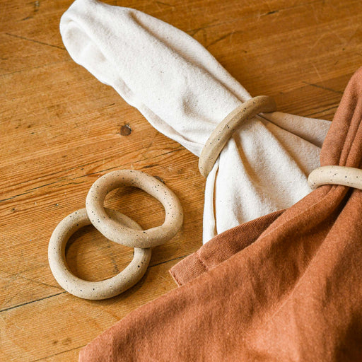 Two sets of ceramic napkin rings. One set on the Ware napkins. One set sitting alone.