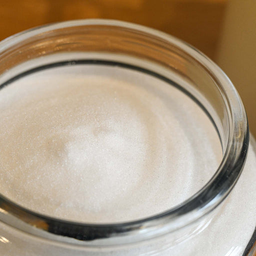 Bulk citric acid in a glass jar without a lid.