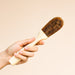 Handheld coconut coire dish brush with wooden handle.
