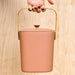 Hand holding bamboo compost pail bin in terracotta.
