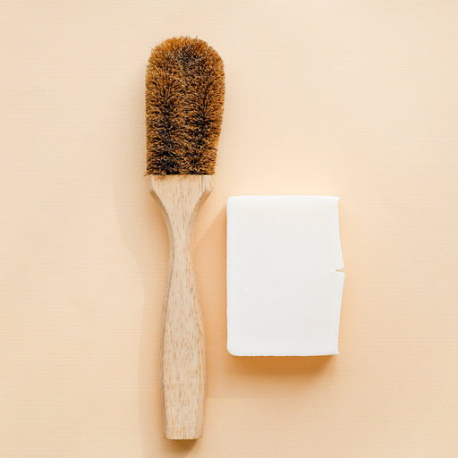 Coconut coire dish brush with wooden handle. Next to unpackaged dish block.