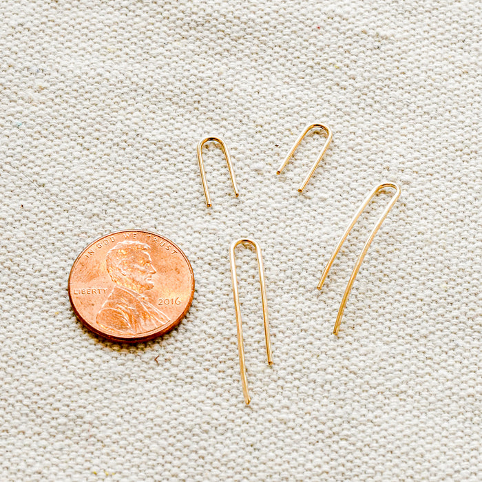 Ear pin staples in short and long, 14k gold. Penny for size comparison. 