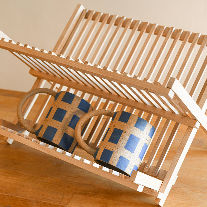 Beechwood foldable dish drying rack with two mugs on the bottom.