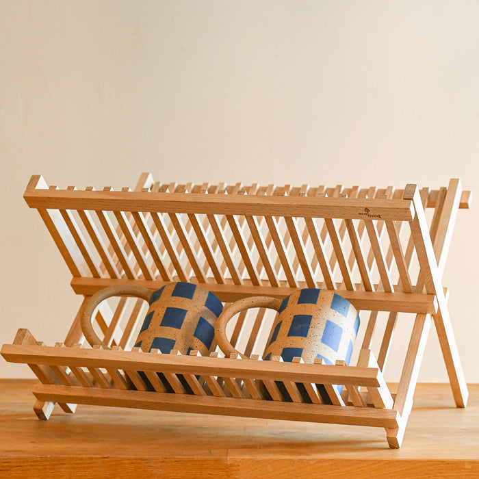 Beechwood foldable dish drying rack with two mugs on the bottom. 