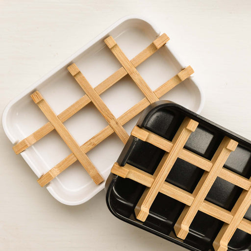 Two bamboo soap dishes. One in white with natural grid pattern. One in Black with natural grid pattern.