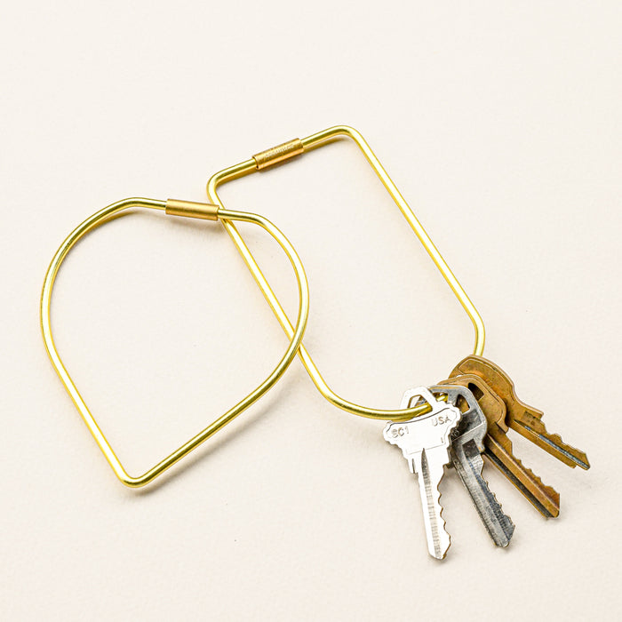 Brass drop and bend key rings. Bend key ring holding keys. Drop key ring bare. Screw closure.