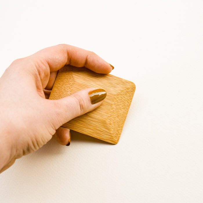 Hand holding bamboo pot scraper.