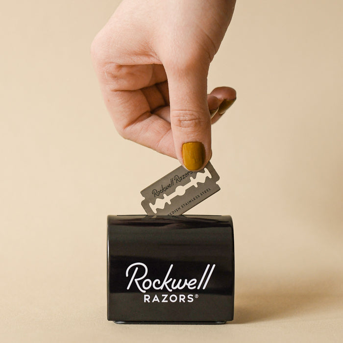 Dropping razor blade into the Rockwell black tin razor bank.