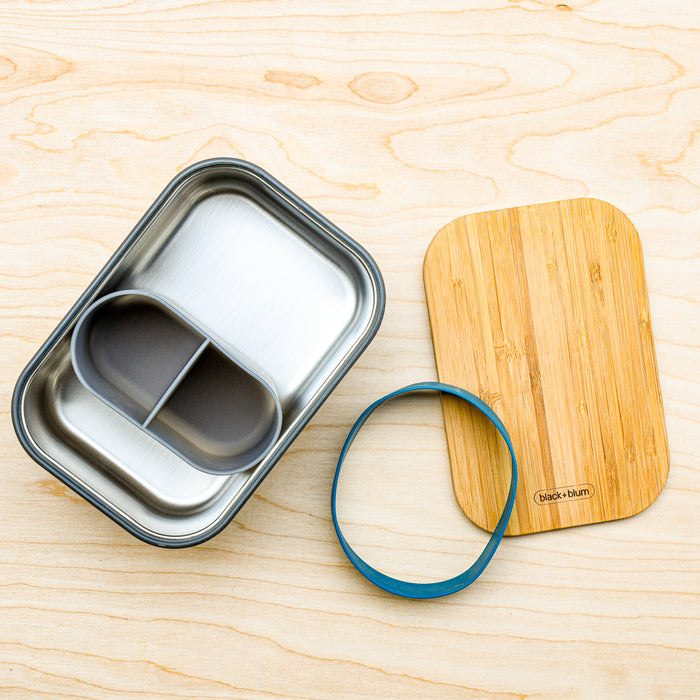 Inside large stainless steel lunchbox with silicone divider. Bamboo cutting board and ocean silicone gasket. From Black and Blum.