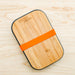 Stainless steel sandwich box with bamboo cutting board lid and  silicone gasket in orange. From Black and Blum.