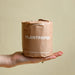 Bamboo toilet paper being held by a hand with paper wrapped packaging. From Plant Paper.