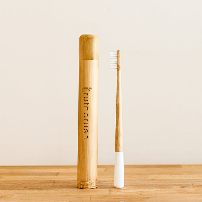 Bamboo truthbrush case with bamboo toothbrush standing beside it.