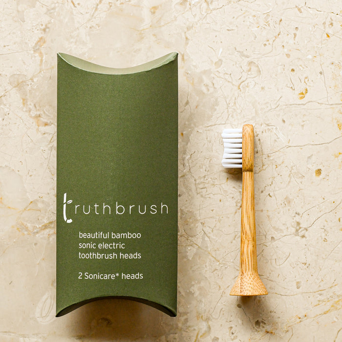 Bamboo electric toothbrush head. One in packaging, one laying next to box.