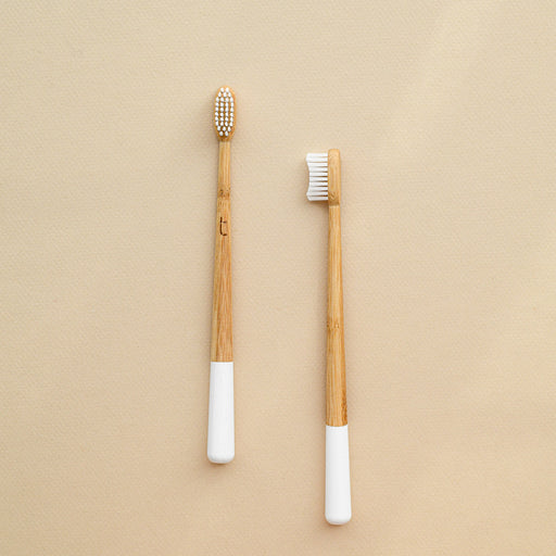 Compostable bamboo toothbrush in soft and medium-firm bristles. White bottom. From Truthbrush.