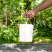 Hand holding bamboo compost pail bin in natural.